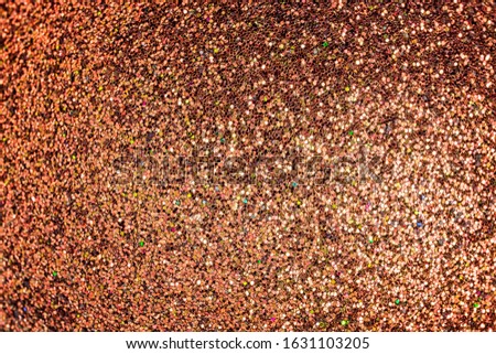 Bright shiny red-gold background for sites and layouts. The surface of many small sparkles, closeup. Selective focus.