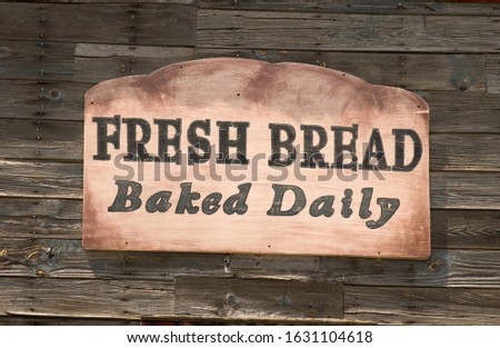 A fresh bread baked daily sign on a wooden wall under the lights at daytime