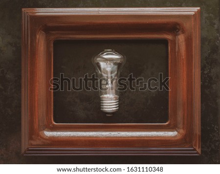 lamp in the frame. Old glass light bulb in a brown frame for painting. idea concept
