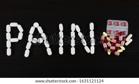 Pills and tablets over black background. Word PAIN made of pills.