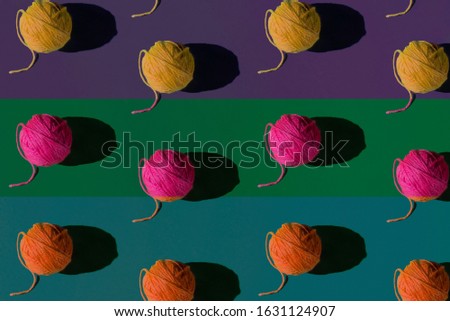 Seamless pattern of colorful yarn (yellow, pink, orange) on color (purple, green, blue) background; flat lay