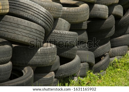Old tires stacked to form a barricade or wall at a fairground to provide a safety feature for participants on rides and amusements Royalty-Free Stock Photo #1631165902