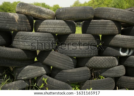 Old tires stacked to form a barricade or wall at a fairground to provide a safety feature for participants on rides and amusements Royalty-Free Stock Photo #1631165917