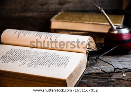 Old books, glasses, calabash, bombilla against the background of old wooden boards, conditions for a deep and pleasant reading.