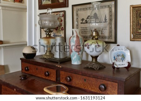 Vintage kerosene lamps and decorative items on a wooden dresser at an antique store.  Maine, USA Royalty-Free Stock Photo #1631193124