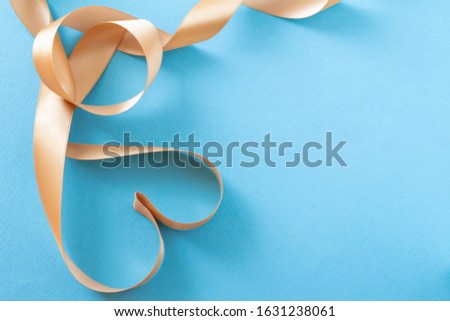 Image of polished present with heart on blue background and gold ribbon
