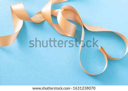 Image of polished present with heart on blue background and gold ribbon
