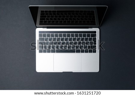 Top view of a modern compact laptop on a dark background. High technology. The laptop screen is open. The concept of a modern gadget. Freelancer's workplace. Black background