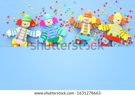 Party colorful noisemaker cute clown doll over blue wooden background . Top view, flat lay