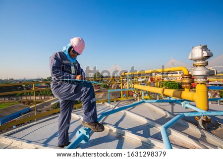 Male worker inspection visual roof storage tank oil background city and blue sky