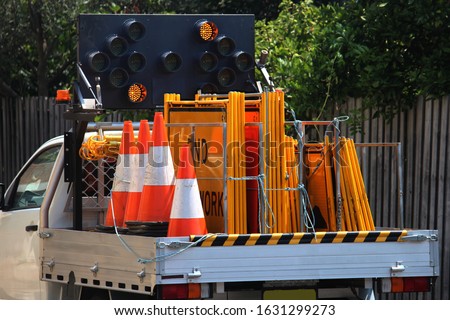 Road construction companies vehicle. The ute loaded with traffic control signage and orange safety cones. Also directional portable traffic lights have been mounted to the back of the vehicle.