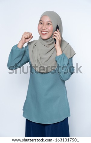Beautiful muslim woman talking on her mobile phone with success expression