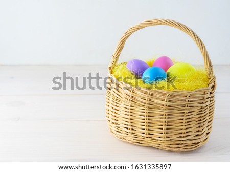 Easter eggs in a basket on a wooden table. Horizontal orientation, copy space.
