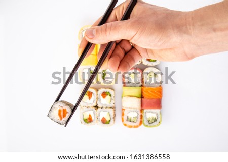 
roll between chopsticks for sushi on the background of a set on a light background for the menu