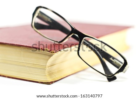 Reading glasses with old book on white background