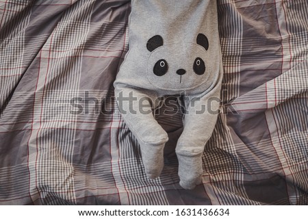 little boy in a panda costume lies on the bed. ass baby