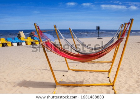 Baltic sea and coast in sunny weather. Rest and relaxation. Several hammocks for relaxing on the beach. Catamarans and a basketball net for recreation and games.
