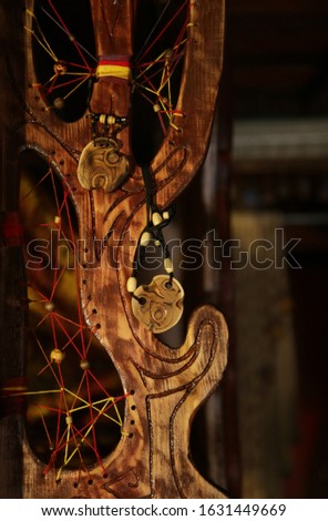 Two wooden amulets hang on carving wooden decorative element of interior. All objects  фку done according to the author’s idea.