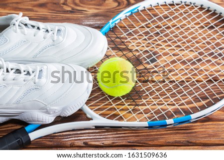 Tennis racket and ball on a wooden background. Photographed in the Studio.