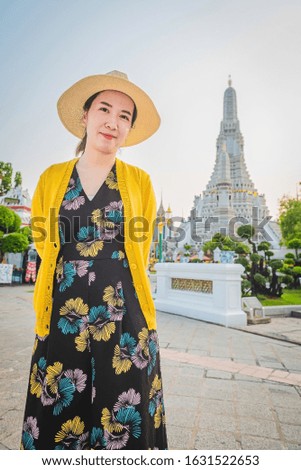 Outdoor portrait of a smiling Asian girl at pagoda of Wat Arun Bangkok, Thailand. Tourist on holiday vacation trips. Travel holiday relaxation. Beauty and lifestyle concept. Selective soft focus.