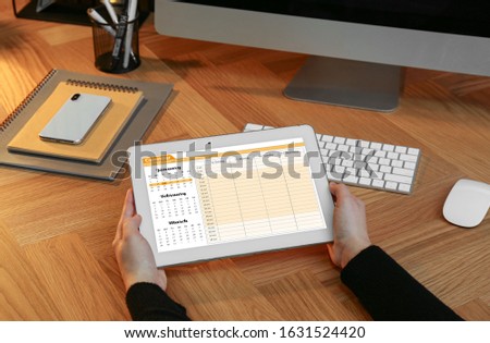 Woman using tablet with calendar app at workplace, closeup