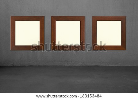 Three blank wooden frames on concrete wall, nobody