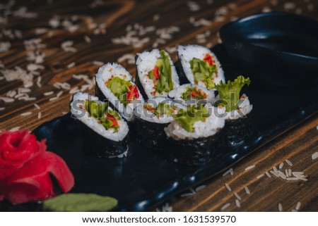 Sushi, rolls, Chinese cuisine,
Seafood, fish, sauces, delicacies.

Black plate food. 
Wooden table.