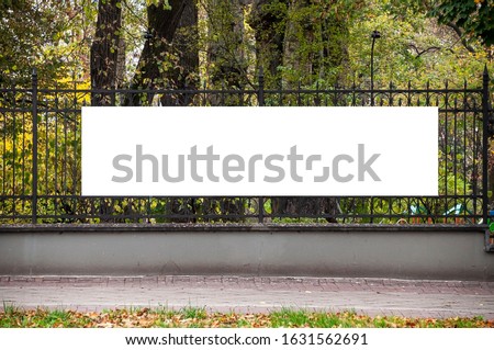 Blank white banner for advertisement on the fence of the park in the city Royalty-Free Stock Photo #1631562691