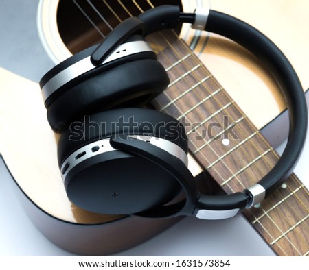 Modern headphones and part of an acoustic guitar.
