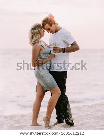 Happy couple drink wine on the beach. Couple in love on sunset background. Valentines day in vacation. Travel, love, youth lifestyle concept. 