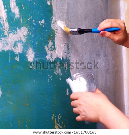 Painting an old wall with a white paint brush. Cosmetic repairs in the house. Updating the walls with paint. Spackled the wall.