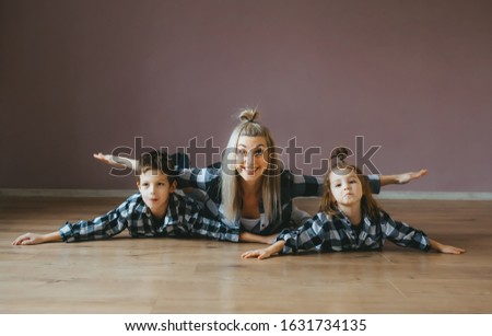 Two kids having fun doing some morning gymnastic with their mother at home. Family doing stretching exercises laying on the floor.
