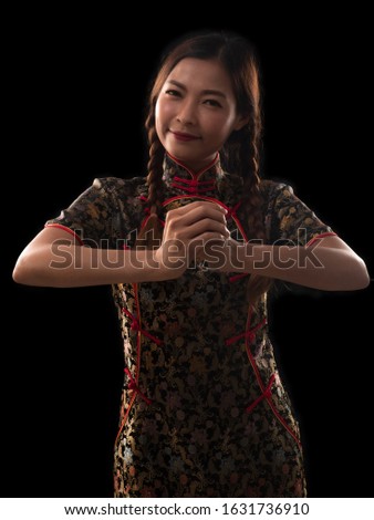 Pretty young woman wearing traditional Chinese dress, qipao, cheongsan with Congratulations, greeting or thank you gesture. Chinese New Year concept.