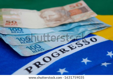 Brazilian money on top of Brazilian flag. Brazilian salary concept. Translation: Progress.