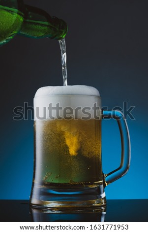 Glass of beer with foam on blue background