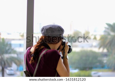 Female photographer with hat and backpack taking photos