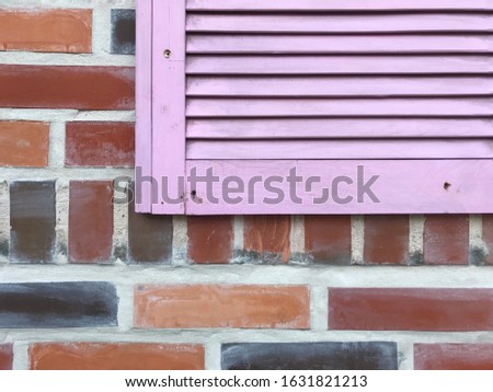 Closeup photo of beautiful house. This building looks like dollhouse. Colorful bricks and pink lattice. Colorful construction background.