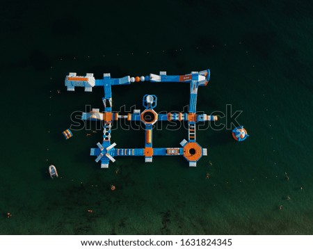 aerial view watersports, sea park, water fun activities,floating slides on the surface of the sea of paradise beach during summer holidays in greece, top down shot drone photos 