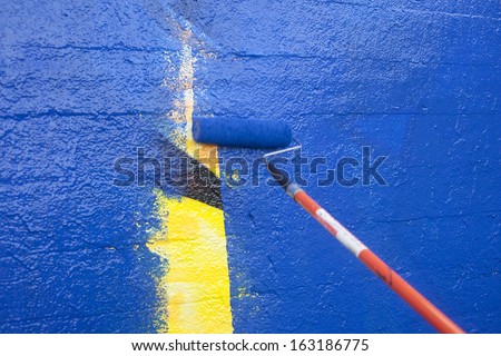 Painting over graffiti on a wall with a paint roller Royalty-Free Stock Photo #163186775