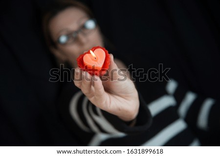 The girl holds a candle in the shape of a heart