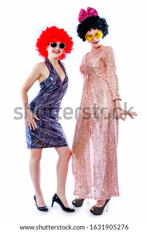 Attractive playful young women ready for carnival parties. Lifestyle and the concept of friendship: a group of two girl friends. Isolated on gray