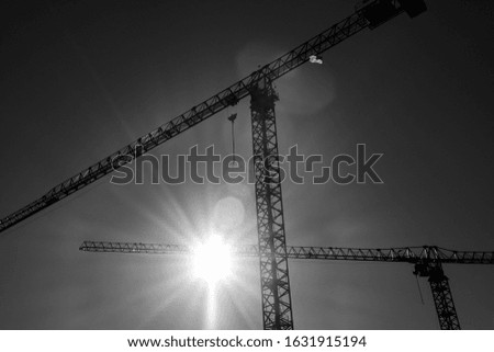 A low angle greyscale of construction cranes under sunlight in Charlotte in North Carolina