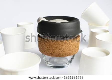Reusable Coffee Eco Cup. Toughened Glass Cup & Natural Cork Band. Secure silicon lid. Reusable eco cup on the background of disposable cups. Eco-Friendly, Spill Proof Travel Mug with Lid | Black