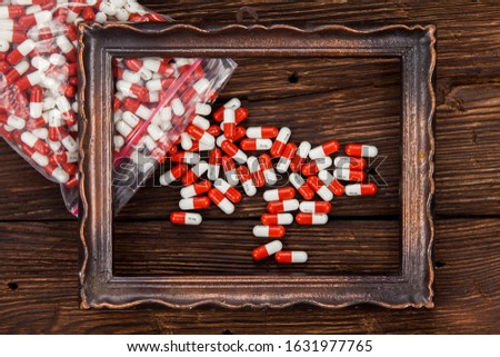 A large number of white-red tablets lie on a brown wooden desk