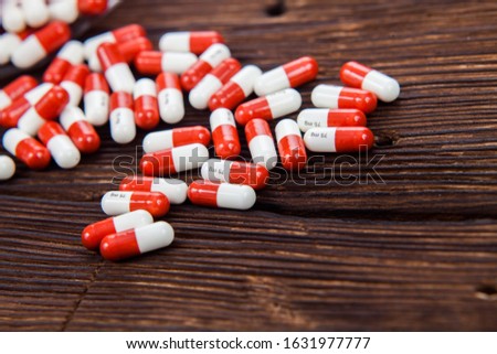 A large number of white-red tablets lie on a brown wooden desk