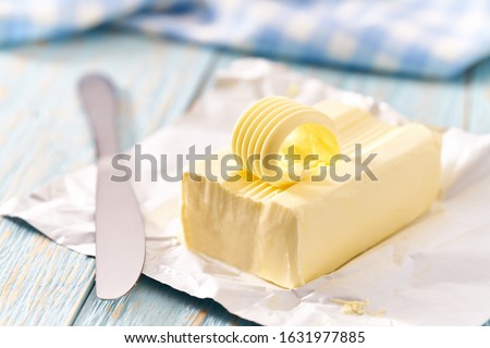 piece of butter on a blue wooden table, selective focus. Royalty-Free Stock Photo #1631977885