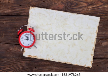 A small red watch lies on an old wooden desk