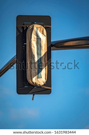 Brand new traffic signals with covers on them waiting to be put in service against blue sky