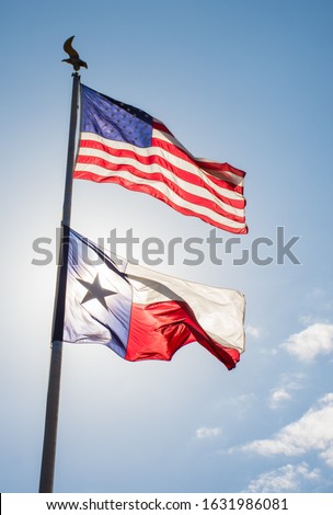 American flad and Texas flag flying on flagpole against blue sky