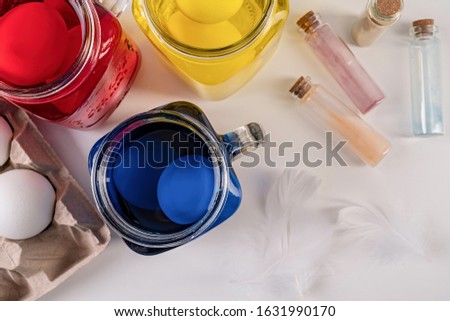 Easter holiday concept. Eggs coloring. Three mason jars with colorful eggs inside on the table